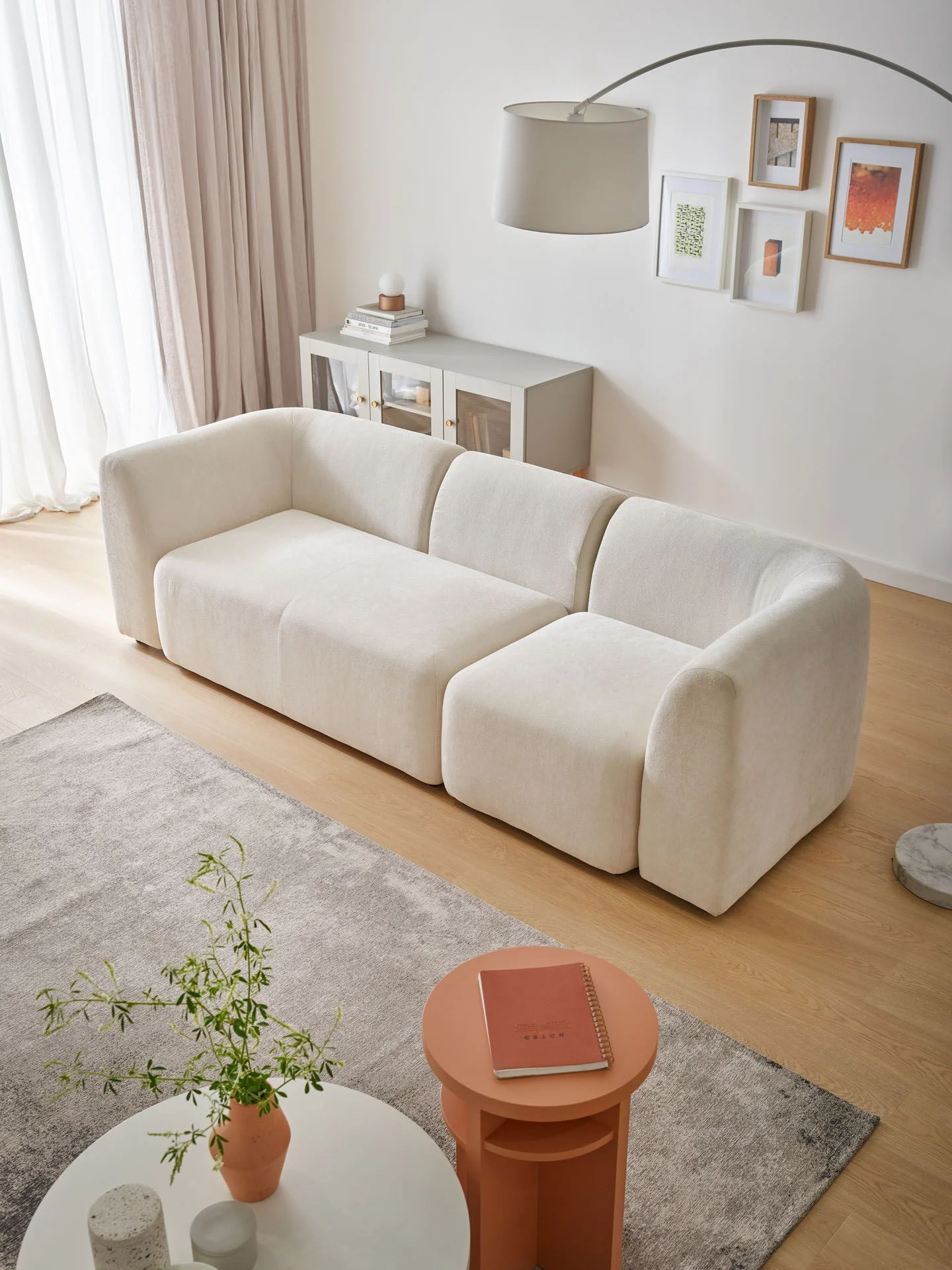 nowoczesna sofa boucle w jasnym kolorze i pastelowe dodatki